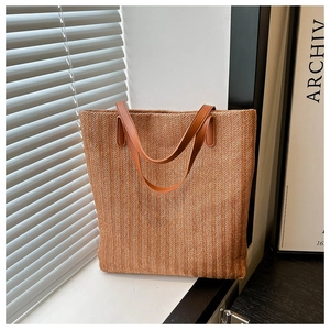 Macro detail of straw woven tote bag featuring herringbone texture and faux leather straps