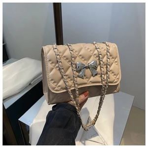 Détail du sac bandoulière beige matelassé avec nœud argenté et bandoulière en chaîne