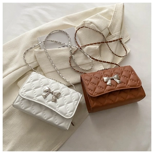 Détail de sacs matelassés blanc et marron avec élégants nœuds en métal argenté