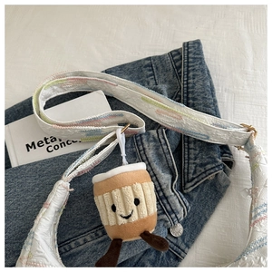 Detail of embroidered rainbow stripes on fabric bag with plush coffee cup charm