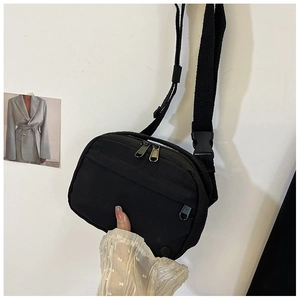 Close-up of black nylon crossbody bag with dual zippers and adjustable shoulder strap
