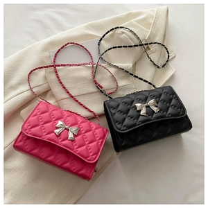 Détail de sacs matelassés avec fermoir nœud argenté et bandoulière chaîne en rose et noir