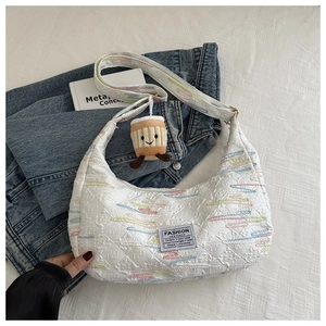 Detail of white striped crossbody bag with colorful embroidery and coffee cup charm