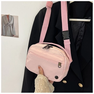 Detail of pink nylon crossbody bag featuring double zippers and wide adjustable strap
