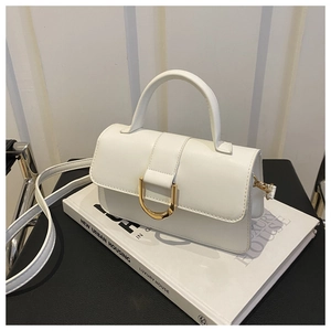 Gros plan d'un sac à main blanc minimaliste avec boucle dorée sur des livres de décoration