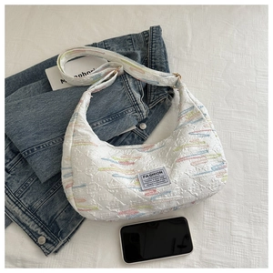 Close-up of textured hobo bag with colorful wave embroidery and Fashion Instinct label