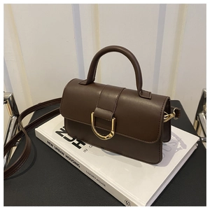 Détail d'un sac à main en cuir marron avec boucle fer à cheval dorée et poignée haute
