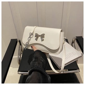 Close-up of white PU leather crossbody bag featuring a silver metal bow and chain strap