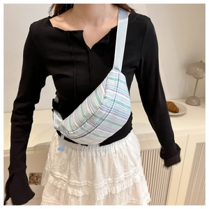 Détail du sac à bandoulière rayé en nylon coloré avec sangle réglable porté par un modèle
