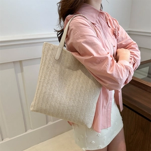 Large beige woven straw tote bag for summer with minimalist V-shaped texture on shoulder strap
