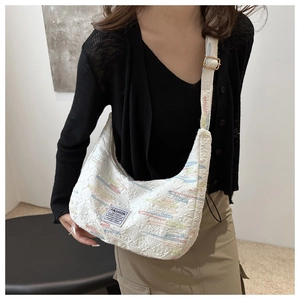 Detail of white crescent crossbody bag featuring colorful embroidery and textured fabric