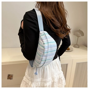 Sac bandoulière rayé bleu et violet porté par un mannequin dans un décor d'intérieur