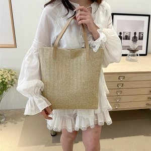 Minimalist straw tote bag with brown leather handles for stylish summer beach vacations