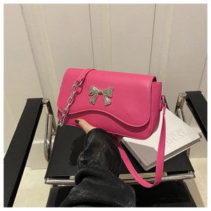 Detail of pink faux leather bag with silver metal bow and chain shoulder strap