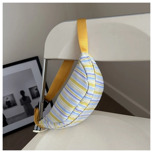 Détail d'un sac bandoulière en nylon à rayures colorées suspendu avec sa sangle jaune