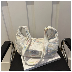 Close-up of white textured shoulder bag with colorful wavy stitching and fashion label