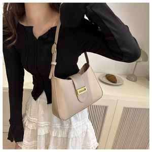 Detail of beige leather hobo bag with gold buckle and adjustable strap on a model