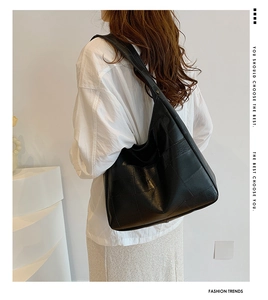 Detail of black large capacity tote bag with geometric leather stitching on model