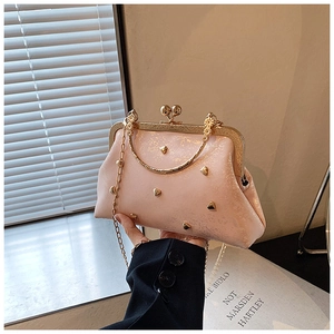 Close-up of pink handbag with golden heart-shaped rivets and vintage metal clasp closure