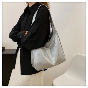 Detail of silver metallic tote bag with geometric pattern worn on a woman shoulder
