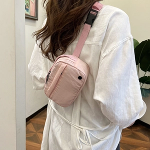 Pink minimalist crossbody bag for travel with adjustable strap shown on model side view
