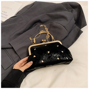 Close-up of black rivet handbag with gold heart studs and metallic sphere clasp detail