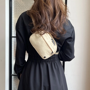 Minimalist beige nylon crossbody bag worn by a model in a black dress, view from behind