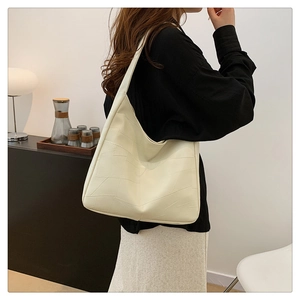 Detail of minimalist beige tote bag featuring geometric stitching and soft leather texture