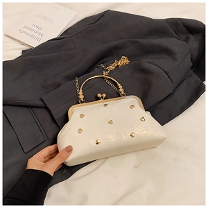 Detail of cream white evening bag with golden heart studs and circular metal handle