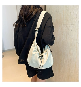 Close-up of beige nylon cloud bag showing puffy drawstring design and wide shoulder strap