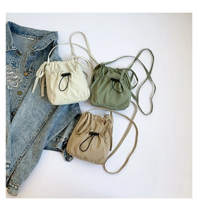 Trois sacs seaux minimalistes en nylon avec cordon en beige, vert olive et kaki