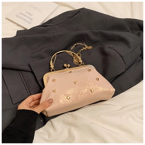 Detail of peach pink clutch bag with gold heart studs and metallic frame closure