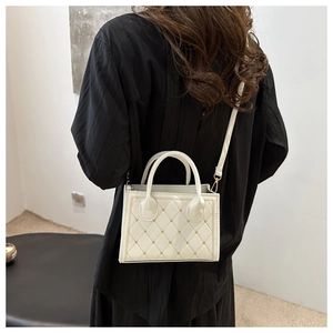Quilted white crossbody bag with gold accents and circular handles shown on a model