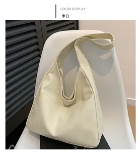Detail view of cream white tote bag with geometric quilting on modern white chair