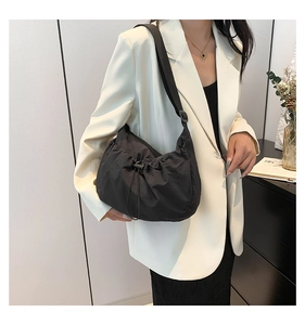 Detail of minimalist black drawstring crossbody bag showing pleated texture and fabric strap