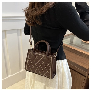 Dettaglio del ricamo a rombi su mini borsa tote marrone con tracolla regolabile dorata