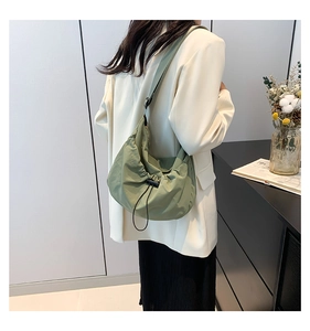 Close-up of light green pleated nylon crossbody bag with black drawstring closure