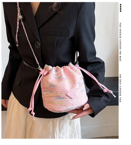 Dettaglio della borsa a secchiello in jacquard rosa con strisce e tracolla a catena
