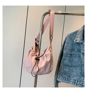 Detailed close-up of pink nylon drawstring crossbody bag with adjustable wide strap