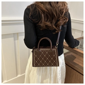 Detail of coffee brown crossbody bag with diamond stitch embroidery and golden hardware