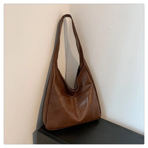 Detail of deep brown tote bag with geometric stitching and minimalist leather texture