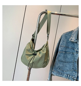 Detail of lime green nylon crossbody bag with adjustable strap and drawstring design