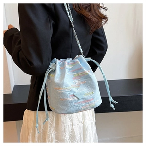Dettaglio borsa a secchiello azzurra con ricami geometrici colorati e tracolla a catena chic
