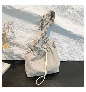 Detail of grey pleated tote bag with silver rhinestones and drawstring closure