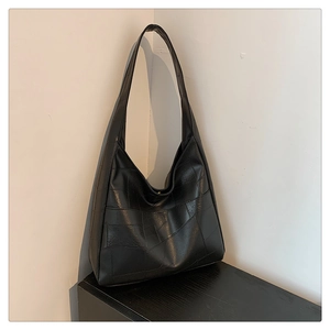 Close-up of black hobo tote bag featuring unique irregular patchwork stitching detail