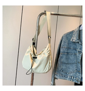 Detail of light beige crescent hobo bag with drawstring pleats and adjustable strap