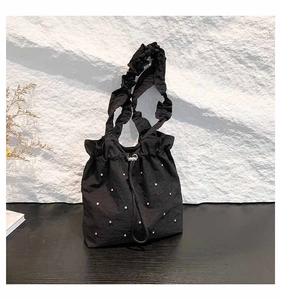 Detail of black drawstring tote with pearl embellishments and ruffled shoulder strap