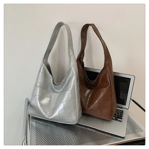Detail of geometric patchwork tote bags in silver and brown on a laptop surface