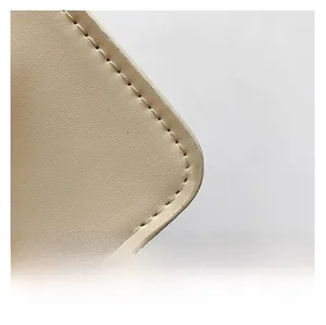 Detailed close-up of beige leather texture and neat stitching on a crossbody square bag