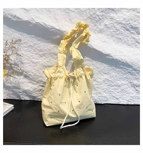 Detail of light yellow drawstring tote with ruffled strap and shimmering rhinestone accents